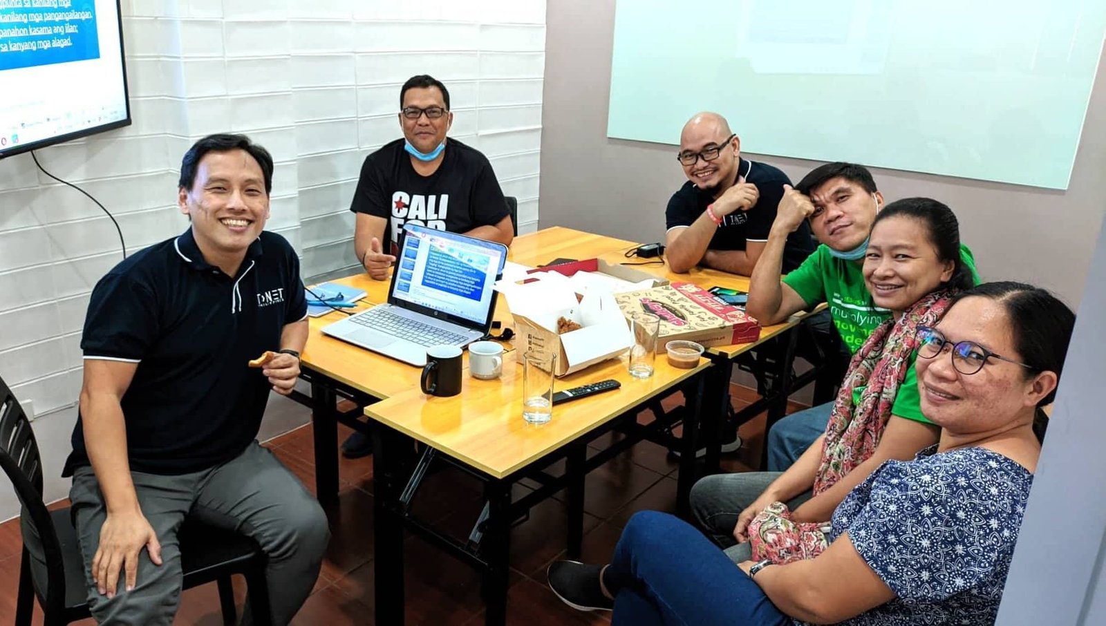 A group of people sitting around a table with laptops.