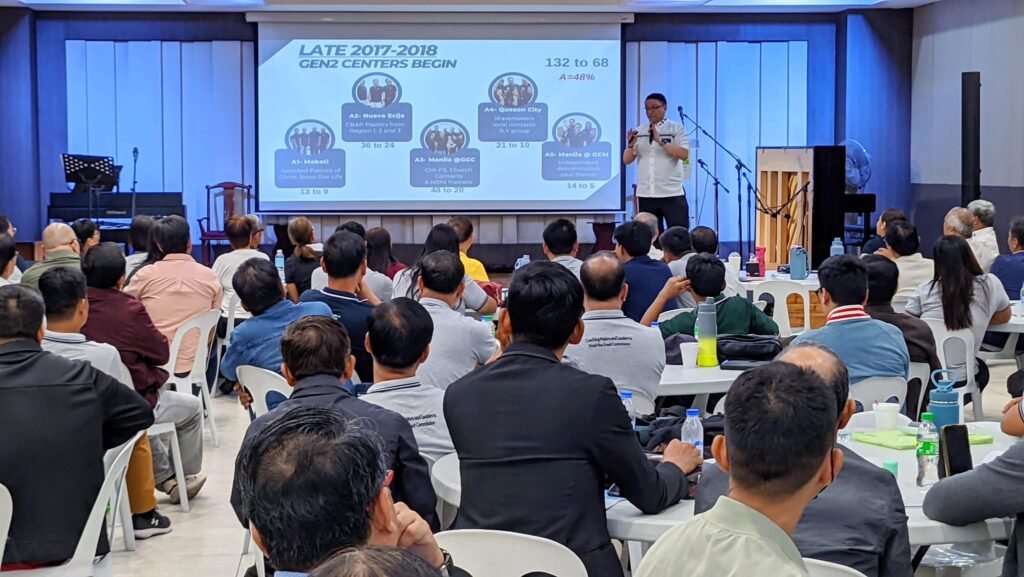 A man standing in front of a large screen at the T-Net Philippines National Gathering.