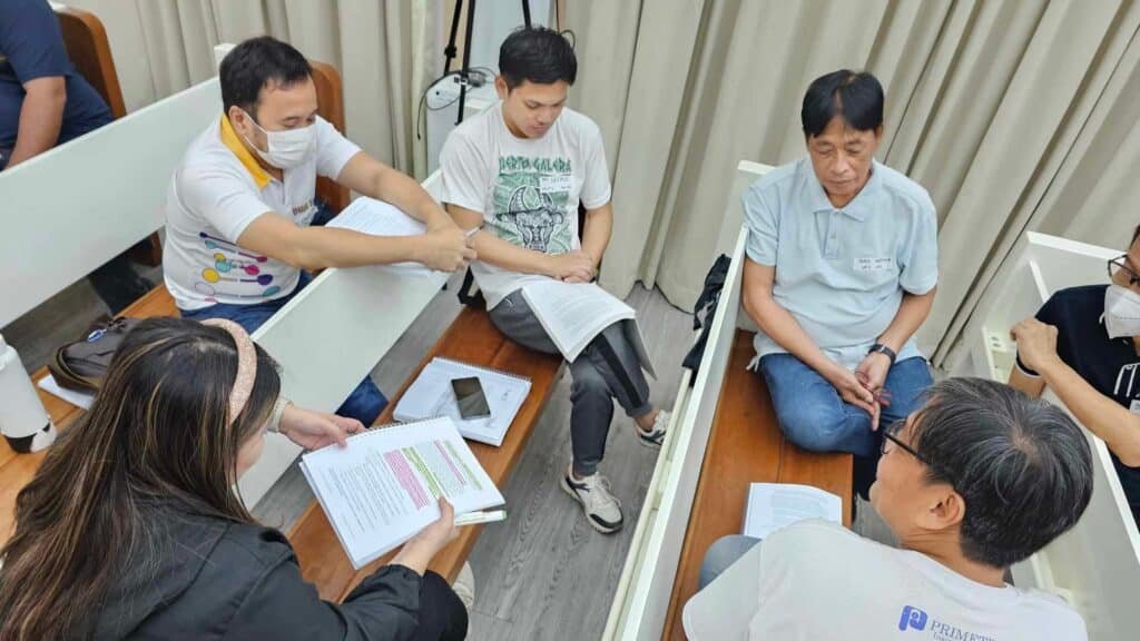 A group of people sitting around a table in a classroom.