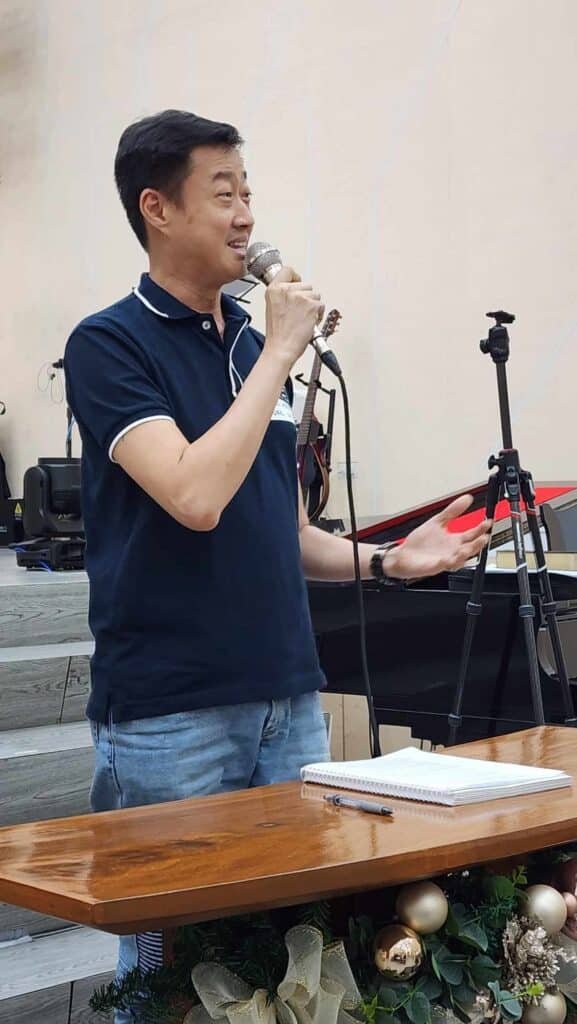 A man holding a microphone in front of a christmas tree.