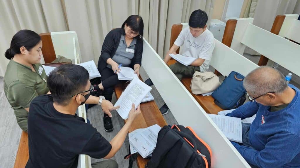 A group of people sitting at a table with papers in front of them.