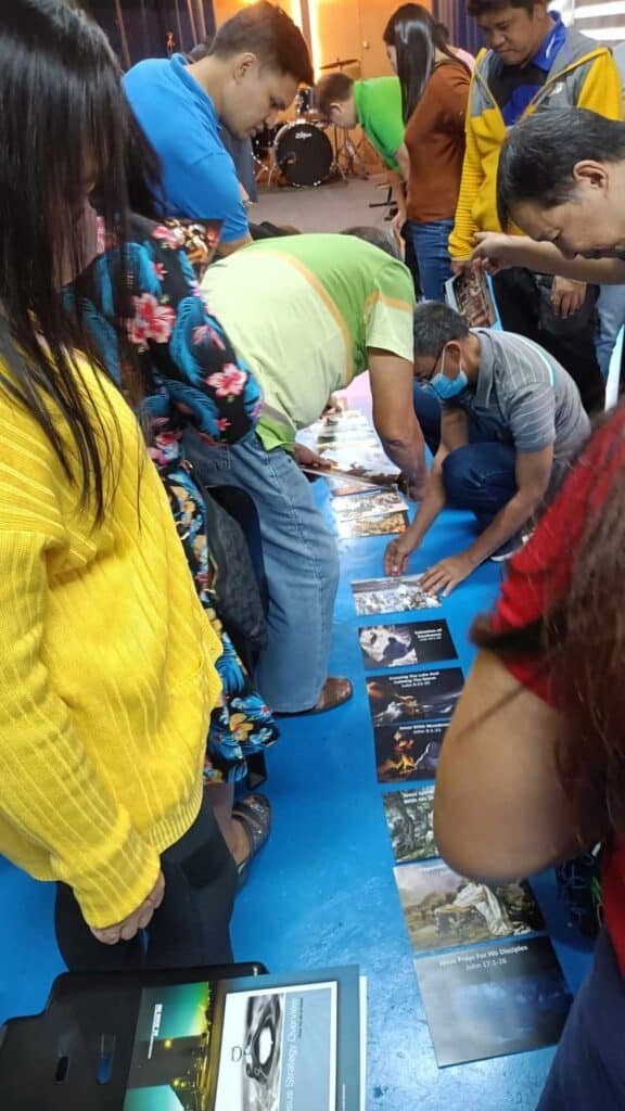 A group of people looking at pictures on the floor.