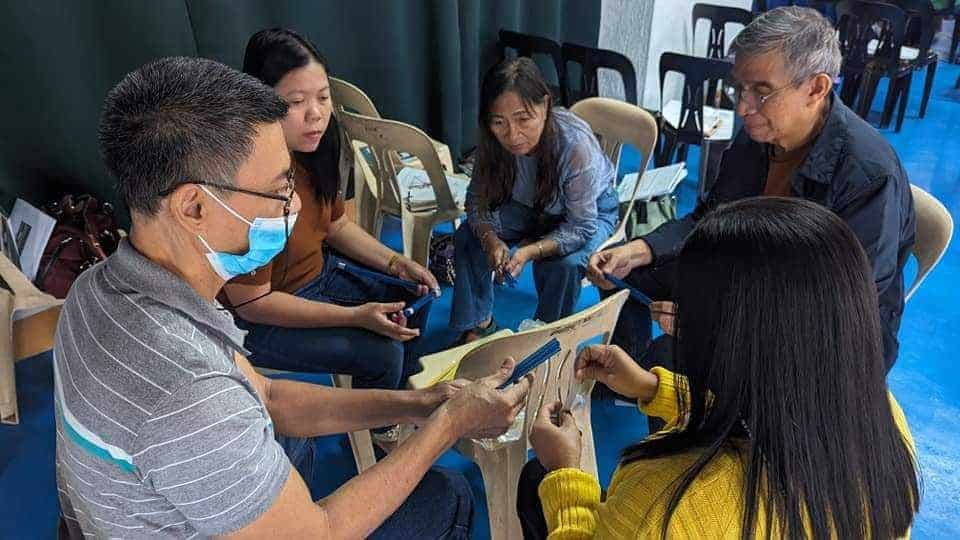 A group of people sitting around a table with masks on.