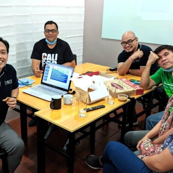 A group of people sitting around a table with laptops.