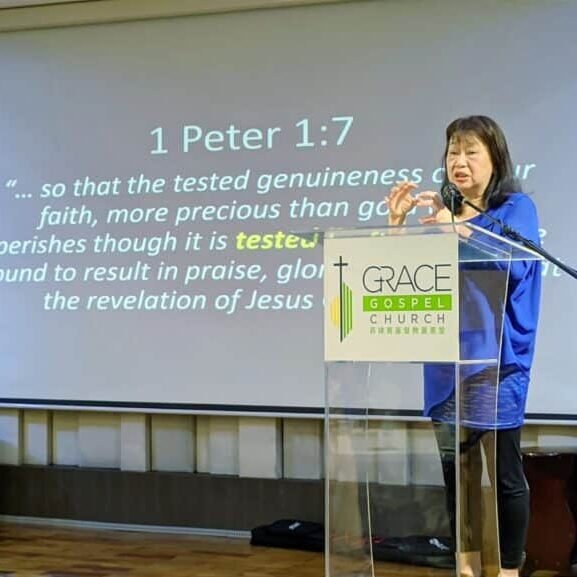 A woman speaking at a podium during the T-Net Philippines National Gathering, in front of a screen.