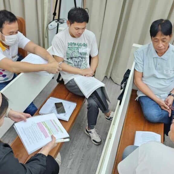 A group of people sitting around a table in a classroom.